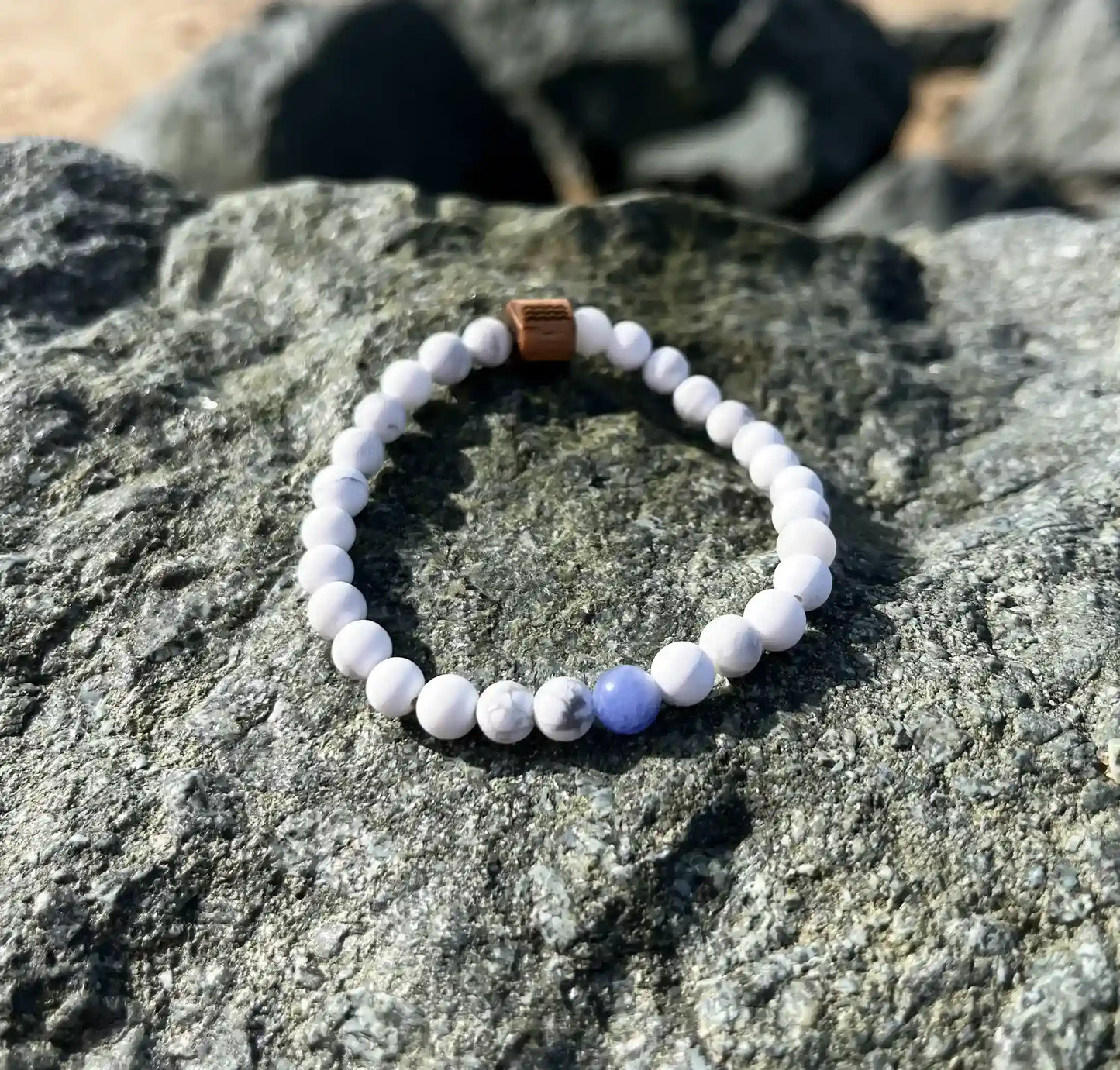 bracelet de perles blanche posé sur un roché