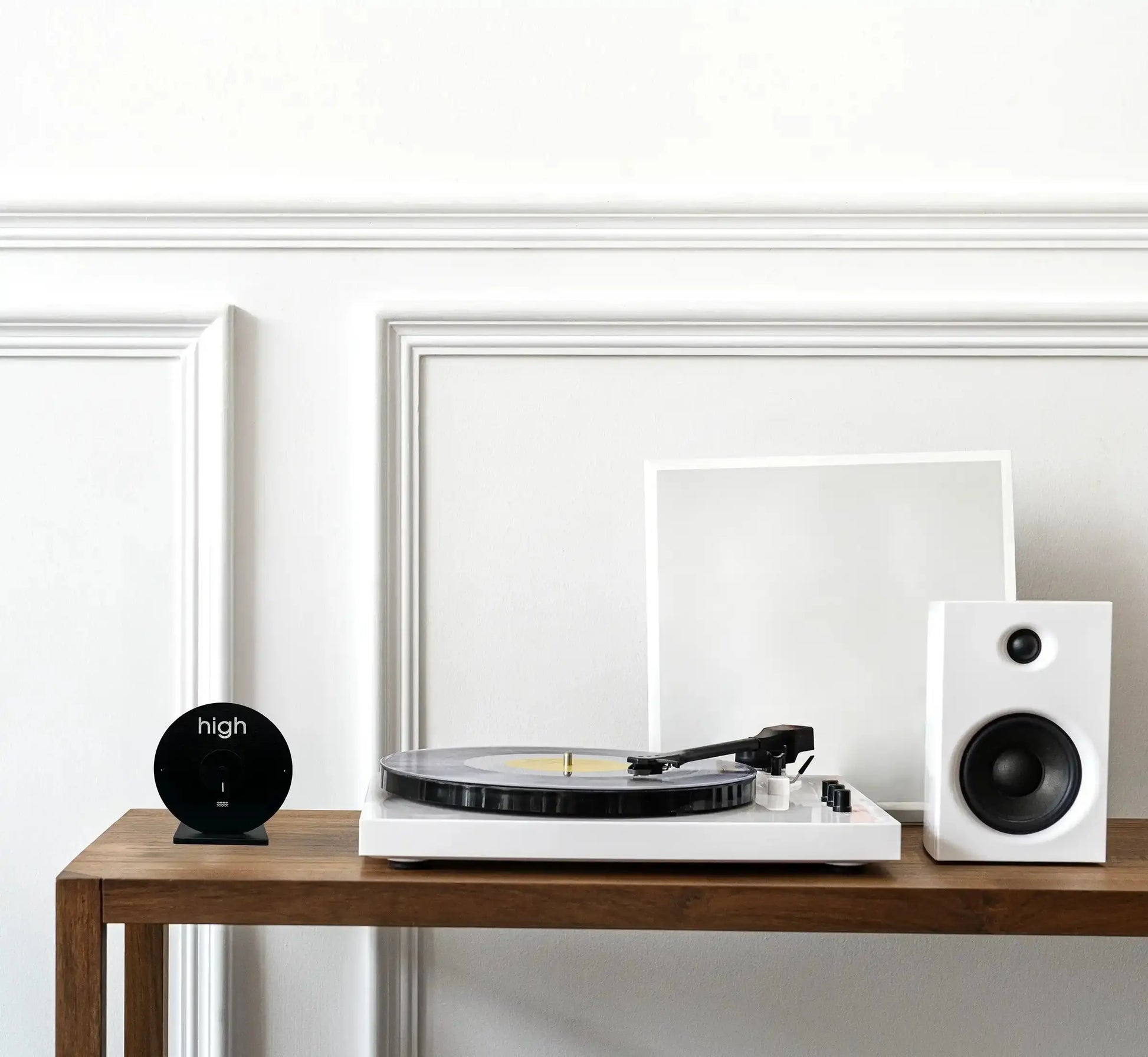 table en bois avec desus : une horloge des marées, une platine disque vinyle et un baffle.