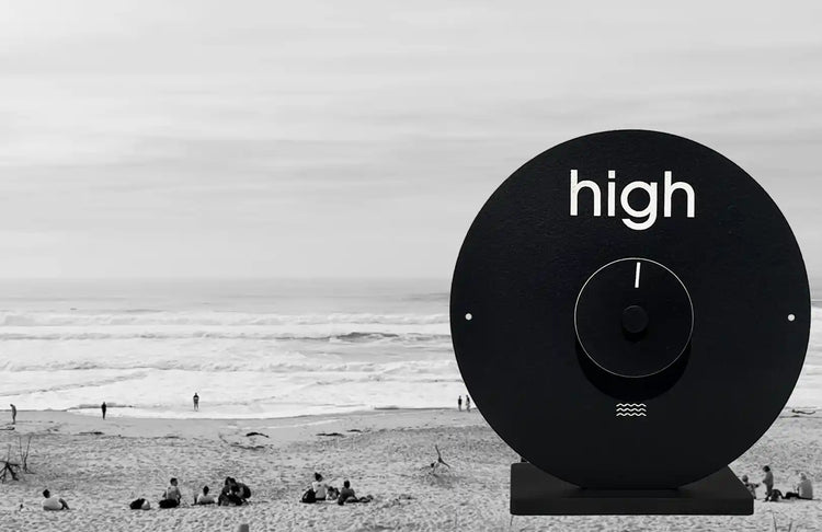 image d'une plage avec l'océan en arrière plan et  une horloge à marée en avant plan 
