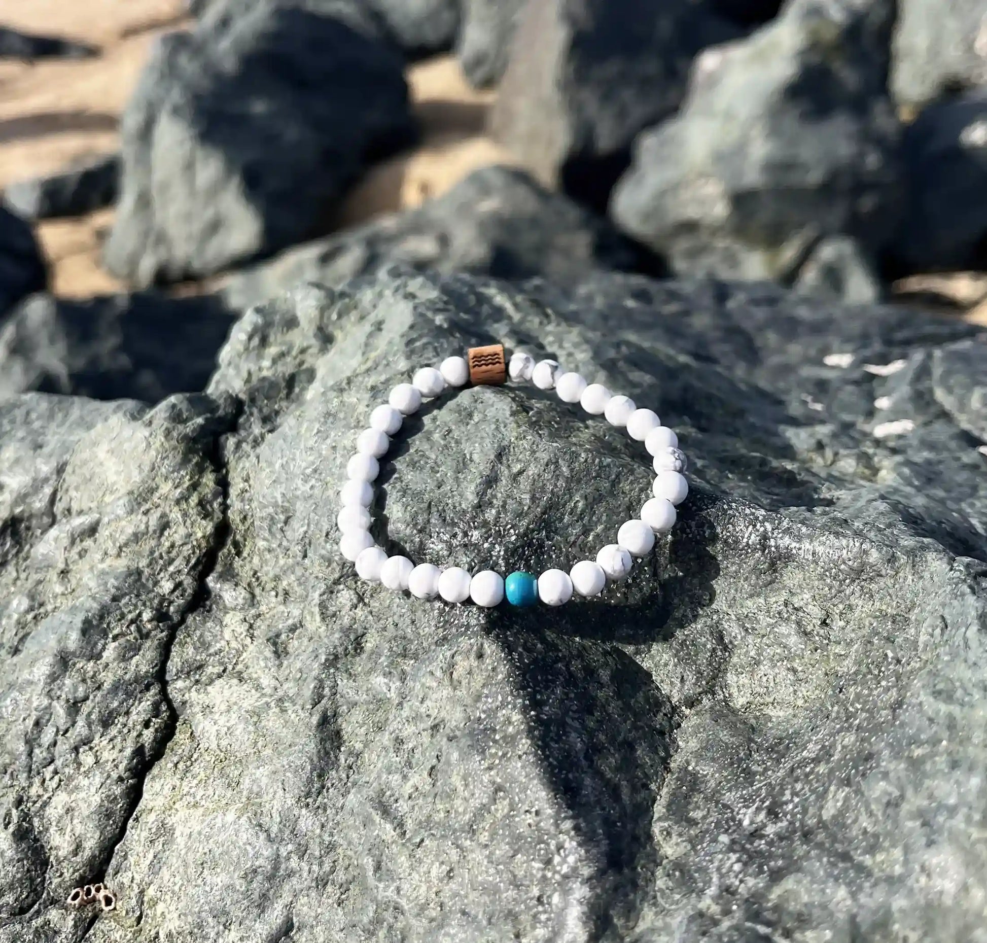 bracelet de perles blanche posé sur un roché