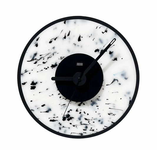 Horloge design blanche tachetée de noirs. 
