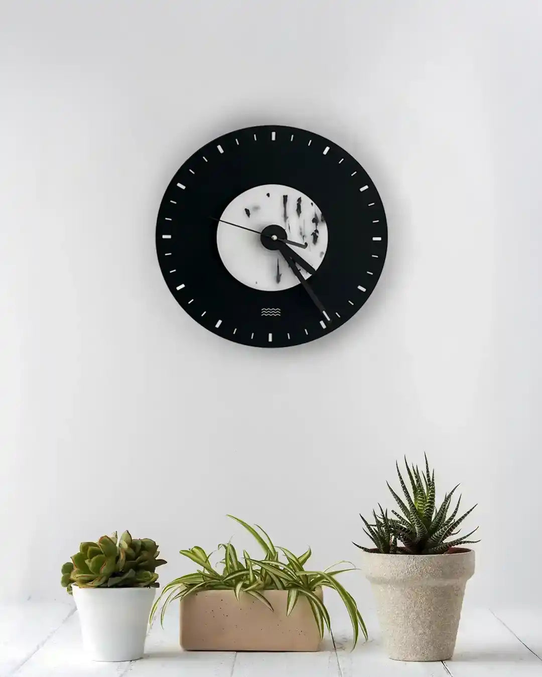 horloge noire et blanche au mur avec un avant plan de cactus