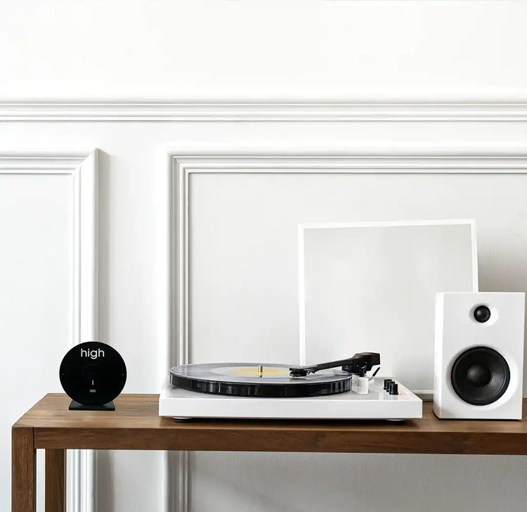 table en bois avec desus : une horloge des marées, une platine disque vinyle et un baffle.